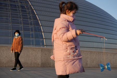 A girl wearing a face mask plays with a diabolo near the National Centre for the Performing Arts, following an outbreak of the novel coronavirus in the country, in Beijing, China February 22, 2020. REUTERS/Stringer