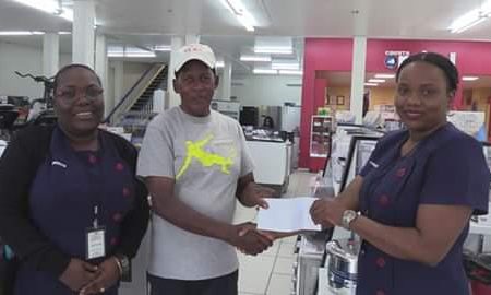 Cycling coach, Randolph Roberts receives the sponsorship cheaque from Assistant Manager, Shellon Amin in the presence of Assistant Manager, Inaz Murray.

