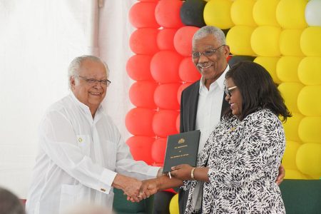 Sir Shridath Ramphal (left) presents a copy of the first Constitution of Guyana after it attained Republican status to Minister of Foreign Affairs, Dr. Karen Cummings as President David Granger looks on. (Ministry of the Presidency photo)
