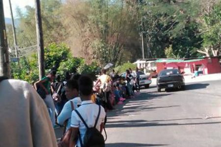 Dozens of students stand along the roadway outside the gates of Oberlin High School in Lawrence Tavern, St Andrew, on Friday. The students were locked out of Jamaica Day celebrations because they wore ripped jeans.