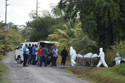 Undertakers remove the bodies of a man and a woman which was found in a vehicle Arouca yesterday morning in a track off Farmer’s Extension, Lopinot Road, Arouca.  