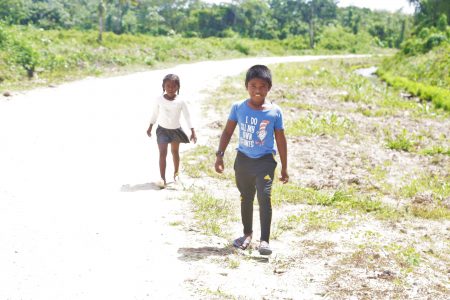 A brother and sister from the neighbouring Bendorff
community make their way along the road in Larimakabra to the shop
situated more than a mile away from
their home
