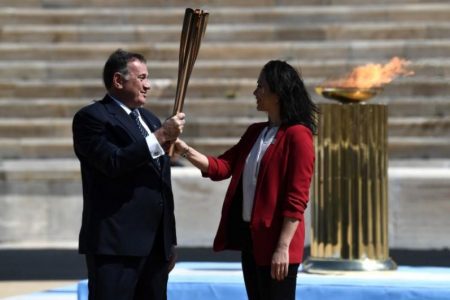 Greek Sports Minister and HOC President Spyros Capralos hands the Olympic torch over to former Japanese swimmer Imoto Naoko during the Olympic flame handover ceremony for the 2020 Tokyo Summer Olympics yesterday. (Aris Messinis/Pool via REUTERS)

