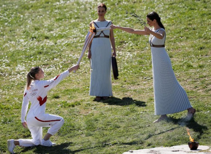 Greek actress Xanthi Georgiou, playing the role of High Priestess passes the flame to the first torchbearer, Greek shooting athlete Anna Korakaki, during the opening of the Olympic flame torch relay for the Tokyo 2020 Summer Olympics yesterday. (REUTERS/Costas Baltas)
