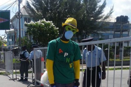 An APNU+AFC supporter, standing at the police barricades near GECOM’s High and Hadfield Street office on Friday, appeared to have adopted extra precaution in wake of the confirmation of the coronavirus in Guyana last week.