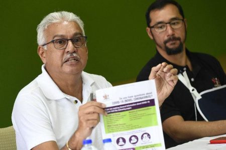 Health Minister Terrence Deyalsingh, left, displays a COVID-19 guidelines poster during yesterday’s news conference at the Ministry of Health on Park Street, Port of Spain. At right is National Security Minister Stuart Young. (Trinidad Express photo)