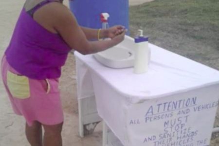 A resident of Coomacka washing her hands at the sanitisation station. (DPI photo)