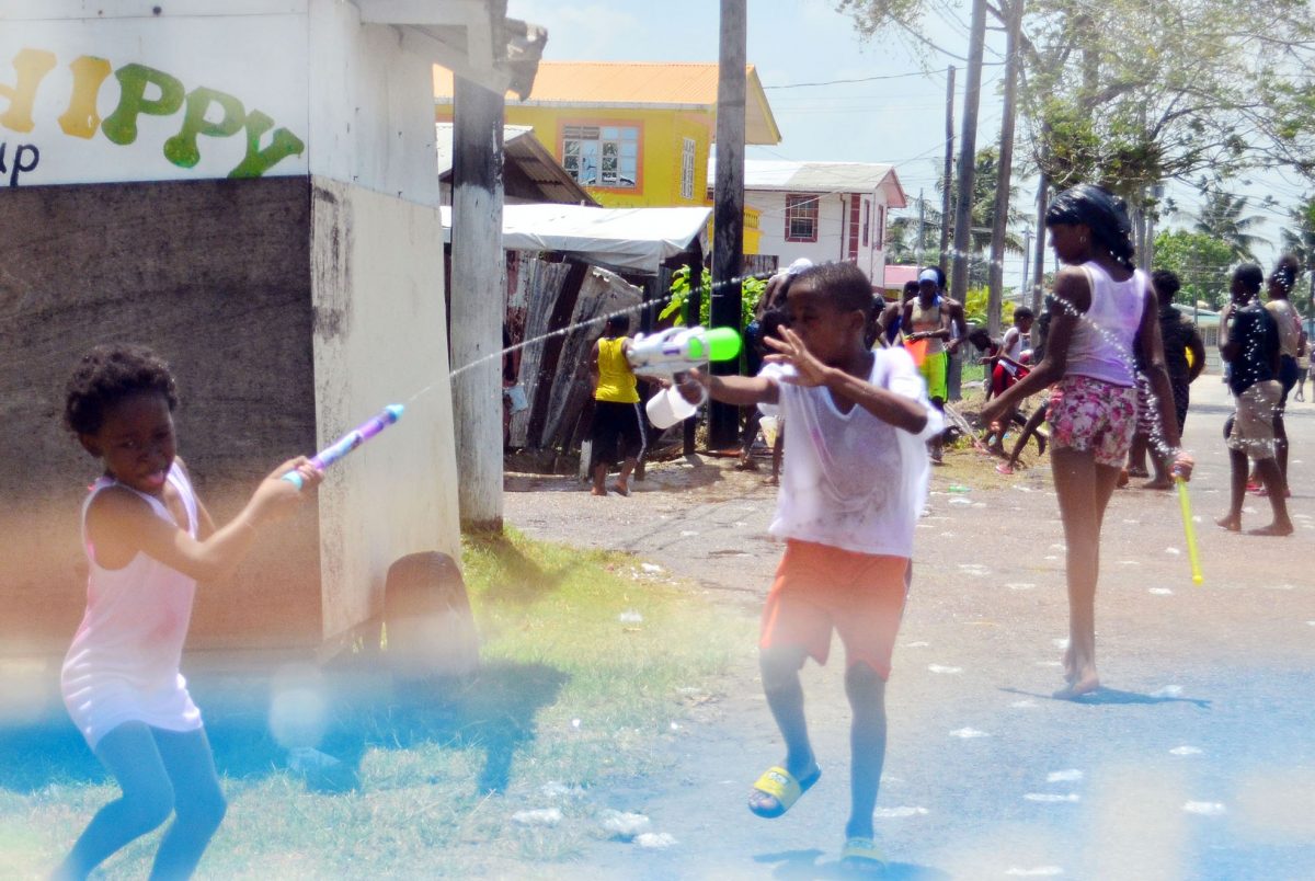 Children playing Phagwah with water guns at Cactus Road, West Ruimveldt