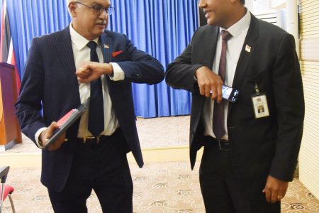 Health Minister Terrance Deyalsingh, left and Chief Medical Officer Dr Roshan Parasram bounce elbows after yesterday’s post-Cabinet press briefing at the Diplomatic Centre, St Ann’s. An elbow bounce is now considered to be a safer form of greeting than a handshake or kiss in the wake of the global spread of the deadly coronavirus.  (KERWIN PIERRE photo)