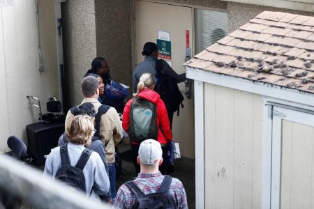 A group of people carrying medical scrubs arrive at the Life Care Center of Kirkland, a long-term care facility linked to several confirmed coronavirus cases, in Kirkland, Washington, U.S. March 8, 2020. REUTERS/Lindsey Wasson
