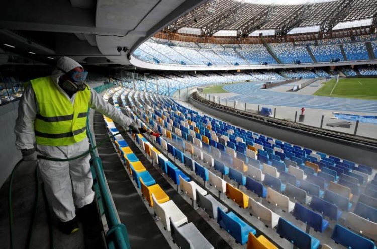 FILE PHOTO: A cleaner wearing a protective suit sanitises seats at the San Paolo stadium ahead in Naples, Italy, March 4, 2020. REUTERS/Ciro De Luca/