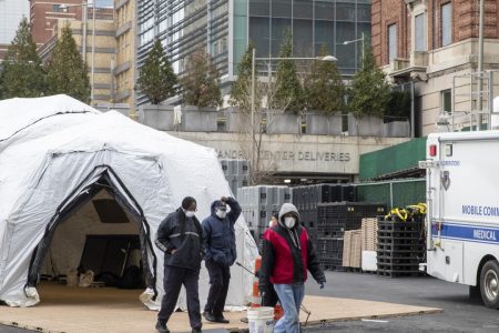 Medical and construction workers are seen at the site of a makeshift morgue that was built outside a hospital in New York on Wednesday.