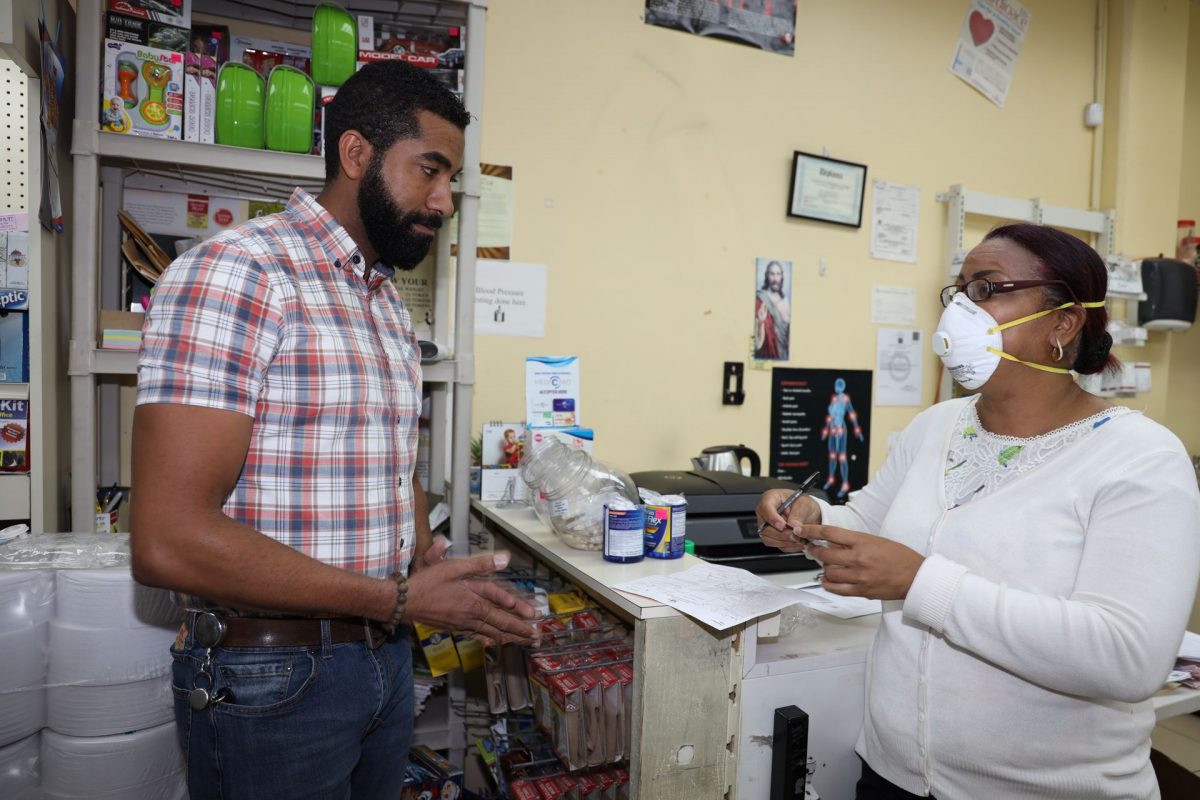 Quik Pharm pharmacist Alana Bosland, right, uses the P2CV N95 respirator coronavirus mask as she attends to a customer at their branch on Frederick Street, Port-of-Spain, yesterday.
