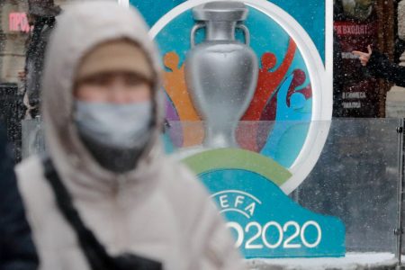 FILE PHOTO: A person wearing a protective face mask walks past the Euro 2020 countdown clock in central Saint Petersburg, Russia on March 1, 2020. REUTERS/Anton Vaganov.