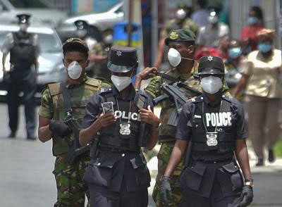 Police officers and members of the defence force walk along Pointe-a-Pierre Road in San Fernando, during a joint-patrol yesterday.