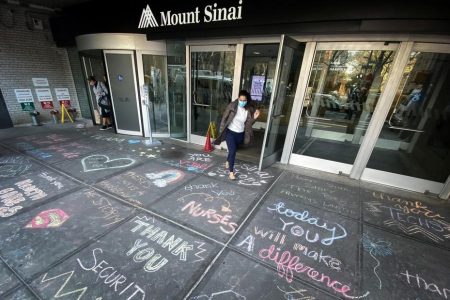 A woman exits Mount Sinai Hospital in Manhattan past messages of thanks written on the sidewalk during the outbreak of the coronavirus disease (COVID19) in New York City, New York, U.S., April 7, 2020. REUTERS/Mike Segar
