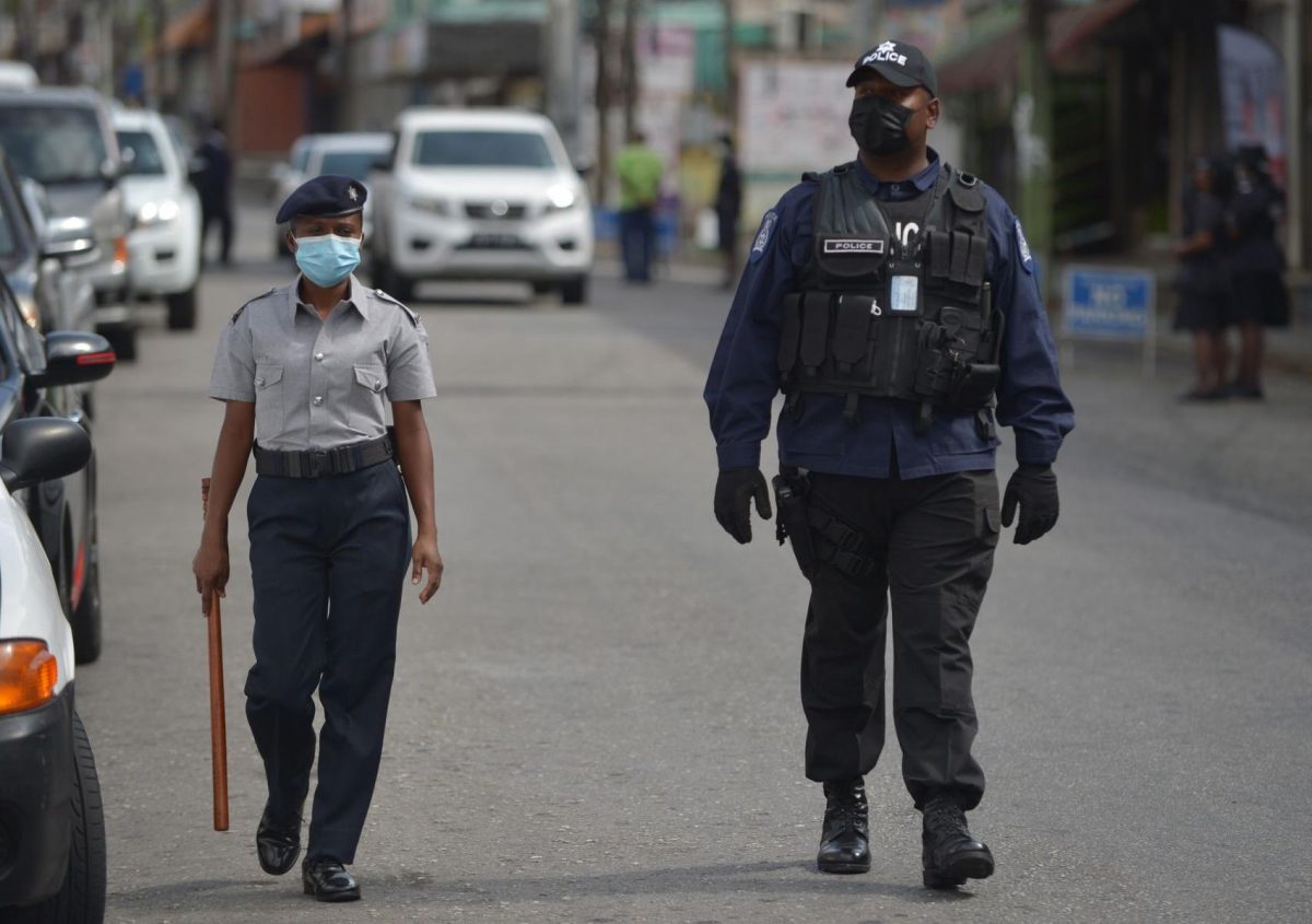 Police officers patrol Mucurapo Street in San Fernando, while observing shoppers at the San Fernando Market yesterday, to ensure they kept social distancing to five-feet in a public space. -Photo: DEXTER PHILIP 