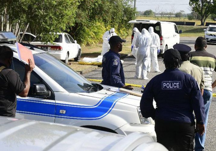 GRIM SCENE: Police officers block the road at Beaulieu Avenue and Fifth Street, Trinicity as undertakers remove bodies of Charmaine James and a man identified only as “Slick” who were found shot dead in a car yesterday.—Photo: JERMAINE CRUICKSHANK