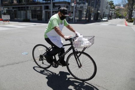A food delivery driver cycles on an empty road as the global outbreak of the coronavirus disease (COVID-19) continues, in Beverly Hills, California, U.S., April 15, 2020. REUTERS/Lucy Nicholson