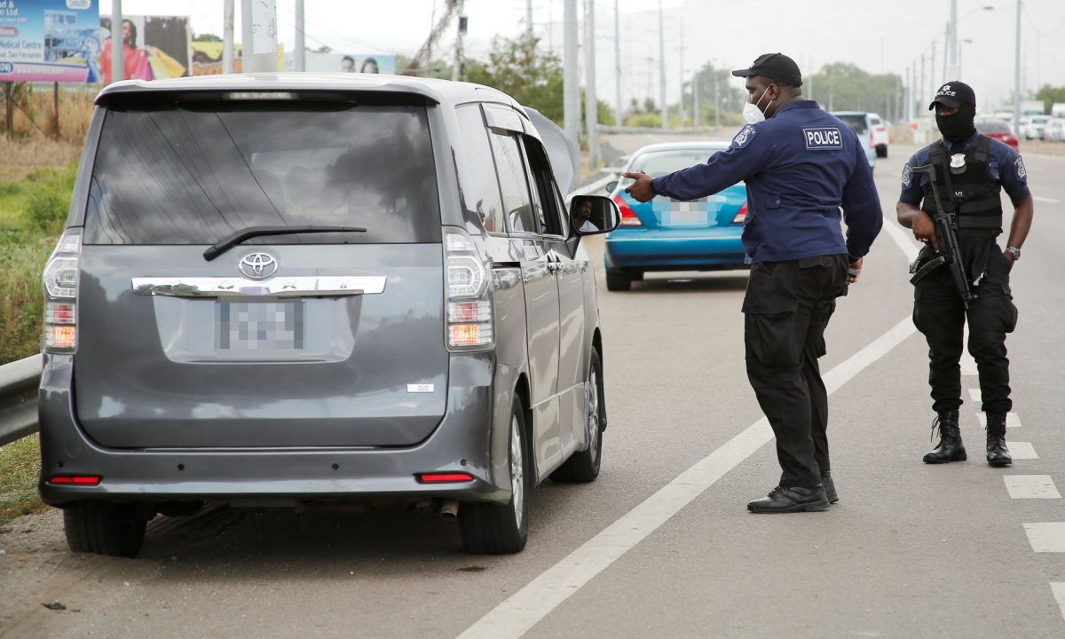 A police officer attached to the Highway Patrol Unit questions a taxi driver who stopped to have lunch on the shoulder on the westbound lane of the Churchill Roosevelt Highway in El Socorro, San Juan, while a roadblock was being conducted on the southbound lane on Friday.