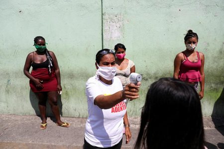 A member of the Socialist party council measures the body temperature of a woman at a checkpoint in the slum of Catia during a nationwide quarantine due to the coronavirus disease (COVID-19) outbreak in Caracas, Venezuela April 15, 2020. REUTERS/Manaure Quintero
