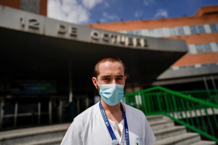 Christian Vigil, 26, an intensive care doctor, poses at the main entrance of the 12 de Octubre hospital during the coronavirus disease (COVID-19) outbreak, in Madrid, Spain, April 8, 2020. REUTERS/Juan Medina