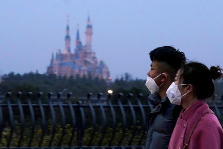 Visitors wearing masks walk by the Shangai Disney Resort, which was closed in January due to the outbreak of the novel coronavirus disease. (REUTERS/Aly Song photo)
