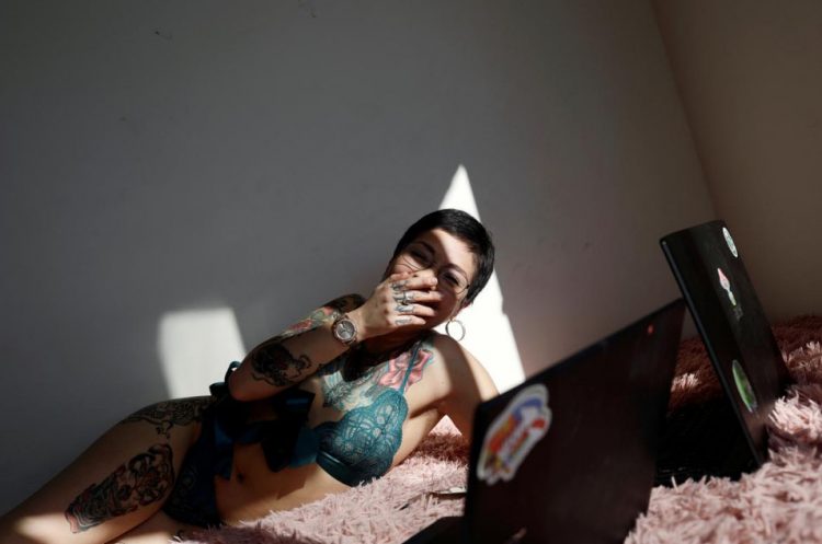 Camila Hormazabal, a 24-year-old sex worker, uses laptops to connect to the web and keep an online erotic meeting with a virtual customer in Concepcion, Chile April 7, 2020. Hormazabal reinvented herself offering sexual services online after the nightclub where she had worked was closed due to the outbreak of the coronavirus disease (COVID-19). Picture taken April 7, 2020. (REUTERS/Juan Gonzalez photo)

