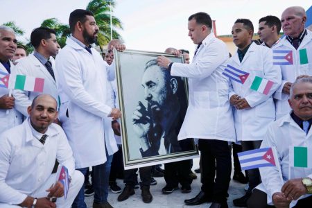 Cuban doctors hold an image of late Cuban President Fidel Castro during a farewell ceremony before departing to Italy to assist, amid concerns about the spread of the coronavirus disease (COVID-19) outbreak, in Havana, Cuba, March 21, 2020. REUTERS/Alexandre Meneghini/