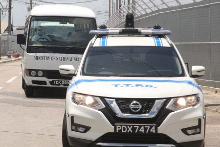 Police escort a vehicle with returning T&T nationals from Piarco International Airport to the National Racquet Centre, Step Down Facility in Tacarigua yesterday.