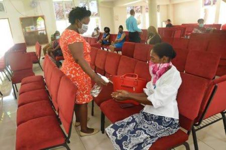 An usher at the King's Seventh-day Adventist Church (left) sanitises the hands of a worshipper at the start of yesterday's service. (Photos: Philp Lemonte)