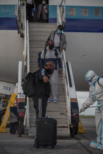 Returning Guyanese nationals were sanitised after they touched down at the Cheddi Jagan International Airport yesterday afternoon. See story on page 11.  (Department of Public Information photo)
