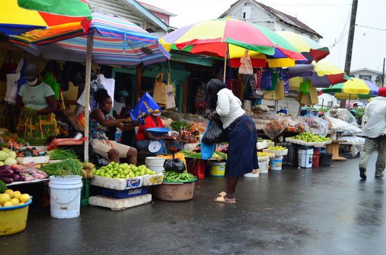 A customer buying vegetables from one of the many stalls along Bourda Street