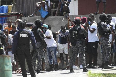 Residents of John John, Port of Spain, clash with police officers during a protest yesterday. 