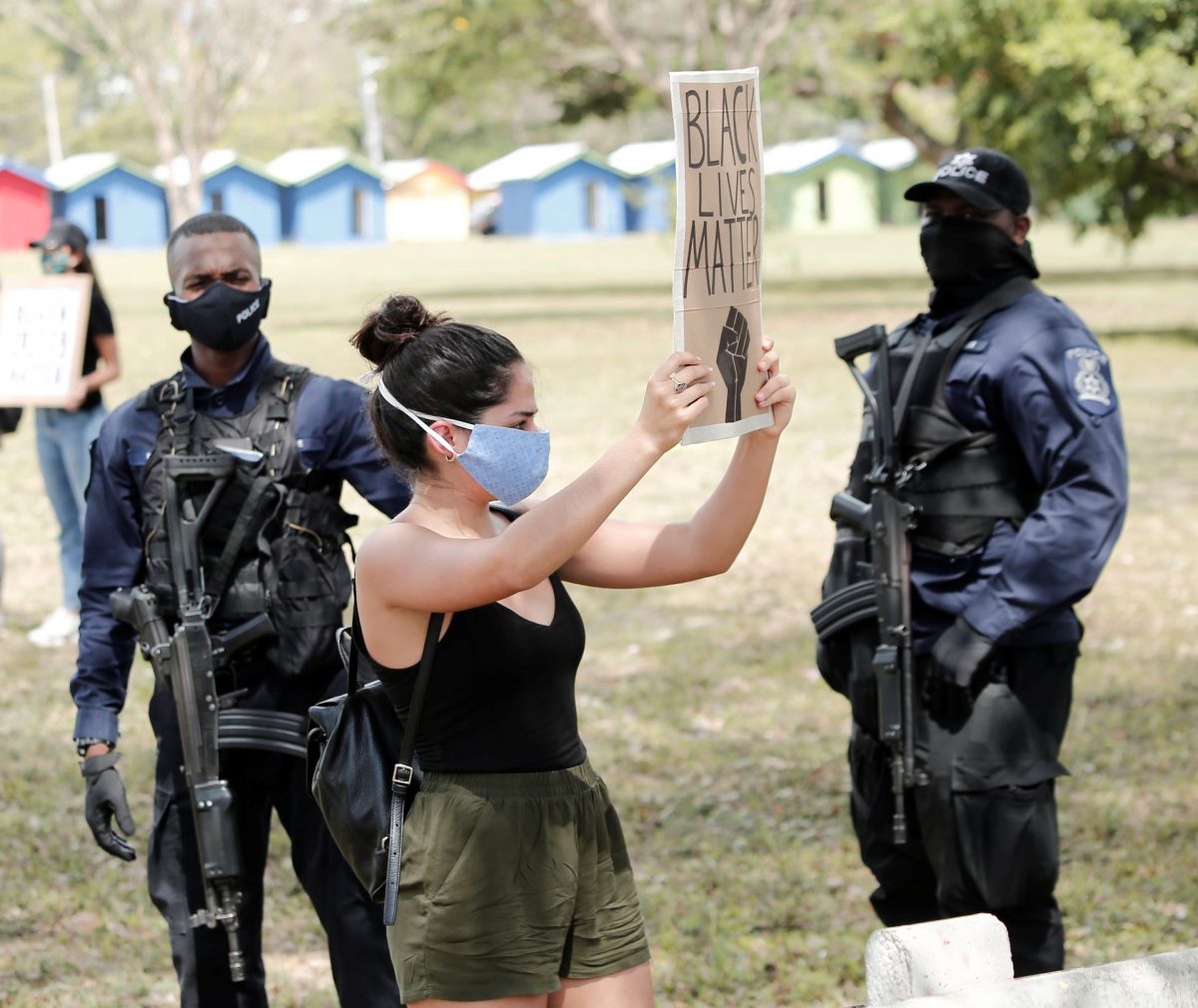 A Black Lives Matter supporter is watched by police during a demonstration at the Queen’s Park Savannah, Port-of-Spain, yesterday.