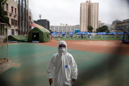 Security staff in a personal protection suit approaches the photographer at a testing site at the Guangan Sport Center after an unexpected spike of cases of the coronavirus disease (COVID-19) in Beijing, China June 15, 2020. REUTERS/Thomas Peter
