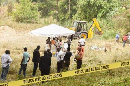 Police and funeral home workers gather at the unofficial burial site at Waterloo Close, bordering Rivoli in Spanish Town, St Catherine, where the skeletal remains of at least two people were found, yesterday. (Photos: Karl Mclarty)
