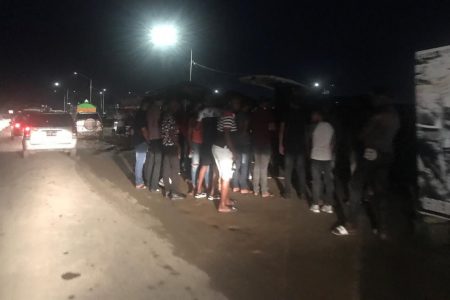 Persons gathered around two vehicles that were blaring music last night
