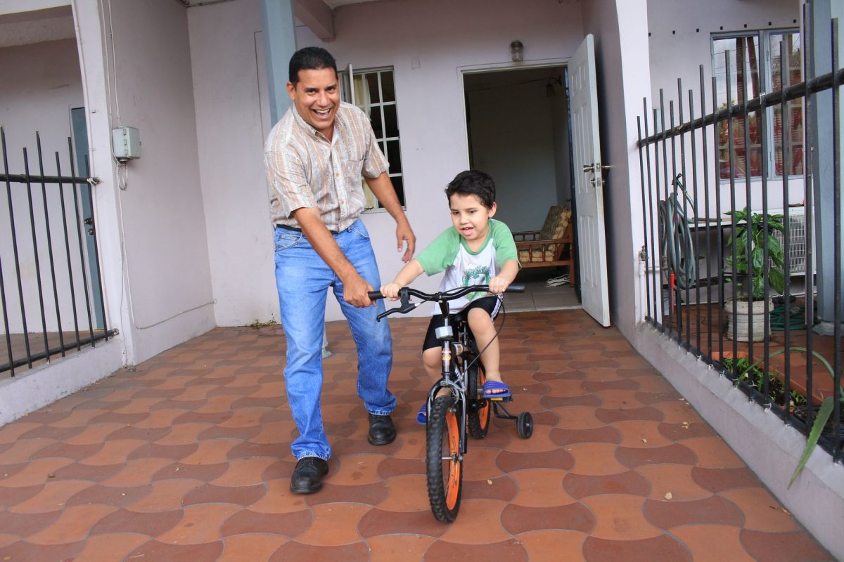 Venezuelan migrant Manuel Romero teaches his son to ride a bicycle at their home at Duncan Village, La Roamine.