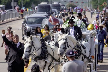 A man raises his hand in solidarity as the coffin of George Floyd, whose death in Minneapolis police custody has sparked nationwide protests against racial inequality, is seen in a horse-drawn carriage as it enters the Houston Memorial Gardens cemetery in Pearland, Texas, U.S., June 9, 2020. REUTERS/Adrees Latif