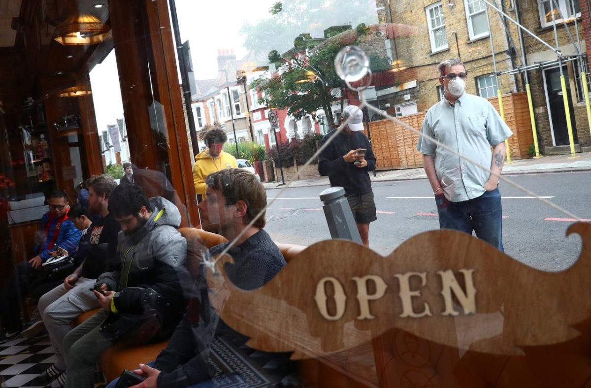 People wait inside and others queue outside Savvas Barbers as it reopened following the outbreak of the coronavirus disease (COVID-19), in London, Britain July 4, 2020. REUTERS/Hannah McKay