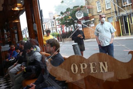 People wait inside and others queue outside Savvas Barbers as it reopened following the outbreak of the coronavirus disease (COVID-19), in London, Britain July 4, 2020. REUTERS/Hannah McKay