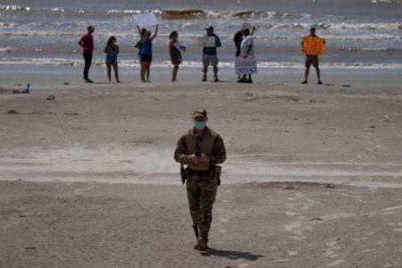 FILE PHOTO: A police officer walks away from local residents protesting closed beaches on the 4th of July amid the global outbreak of the coronavirus disease (COVID-19) in Galveston, Texas, U.S., July 4, 2020. REUTERS/Adrees Latif