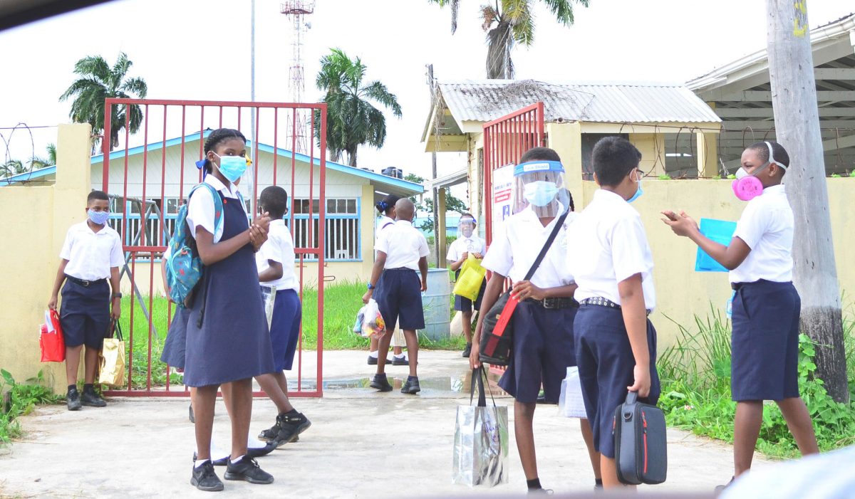 NGSA social distancing: Students practice social distancing as they wait for their parents to pick them up after writing the National Grade Six Assessment yesterday. (Orlando Charles Photo)