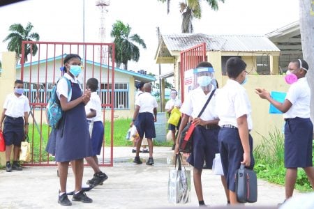 NGSA social distancing: Students practice social distancing as they wait for their parents to pick them up after writing the National Grade Six Assessment yesterday. (Orlando Charles Photo)