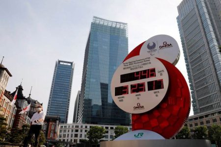 FILE PHOTO: A man wearing a protective mask walks past a countdown clock for the Tokyo 2020 Olympic Games amid the coronavirus disease (COVID-19) outbreak in Tokyo