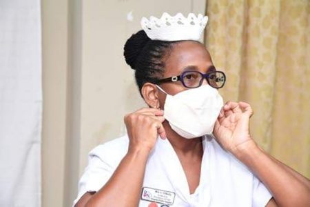 Nurse Charmaine O'Reilly, in-service education officer at Kingston Public Hospital, demonstrates the proper way to put on a face mask in this May 17, 2020 file photo. (Photo: Joseph Wellington)