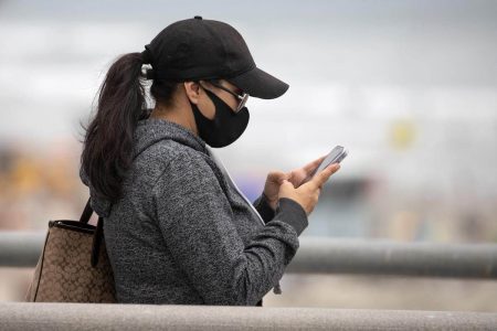 FILE PHOTO: A women wears a face masks as she views her mobile phone during the global outbreak of the coronavirus disease (COVID-19)