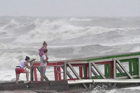 A girl covers her face from strong winds as her family members watch high swells from Hurricane Hanna from a jetty in Galveston, Texas, U.S., July 25, 2020. REUTERS/Adrees Latif