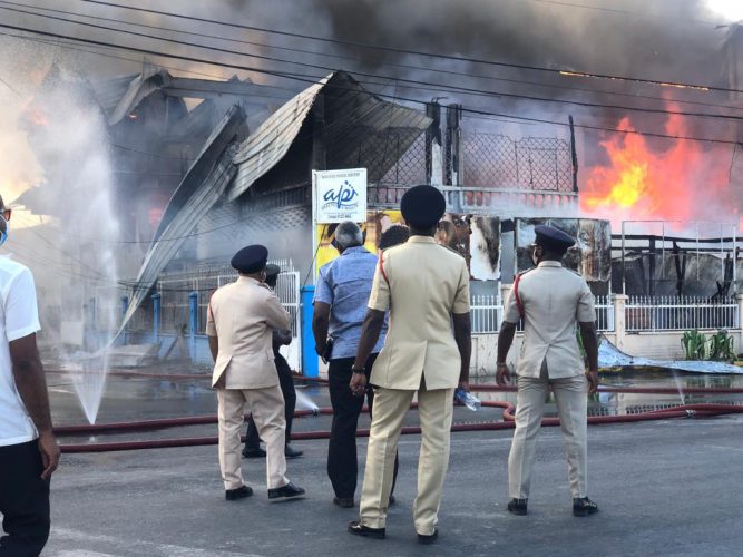 Minister of Home Affairs Robeson Benn surrounded by police and fire officers at the scene of the fire on Sheriff Street on Wednesday afternoon